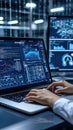 A person is analyzing data on a laptop, illuminated by screens displaying graphs and charts in a dark office setting Royalty Free Stock Photo