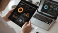 Person analyzing financial data on tablet with laptop showing charts Royalty Free Stock Photo