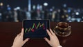 Person analyzing stock market data on a tablet with a cup of coffee at night Royalty Free Stock Photo
