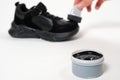 A person applies sponge paint cream to the black crumbs of the child. Care for children's leather and suede shoes.