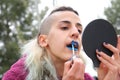 Person applying blue lipstick in front of a mirror