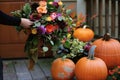 person arranging a floral centerpiece by a pumpkin display