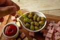 Person arranging olives, cheese, and ham on a wooden board Royalty Free Stock Photo