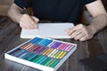 Person, artist painting with a pastel crayon chalk on sketchbook on the wooden table, selective focus Royalty Free Stock Photo