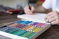 Person, artist painting with a pastel crayon chalk on a white sheet of paper and pellette on the wooden table Royalty Free Stock Photo