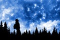 Person with backpack watching the stars in night sky above the pine forest