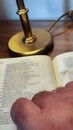 person beginning to read a book or bible to pray at a table with a lamp