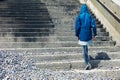 Person in blue jacket walking up stairs outside