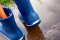 Person in blue rubber boots walking through the puddle Royalty Free Stock Photo