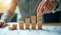 Person builds increasing stacks of wooden blocks on table. Blocks symbolize business process, workflow automation. Image shows