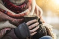 person bundled up in scarf sits, steamy coffee in hand