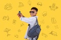 Smiling boy with a backpack holding a smartphone and taking photos