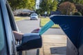 Person in car mailing in absentee ballot at drive-up mailbox on boulevarded street with trees