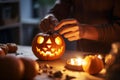 Person crafting a jack-o-lantern in warm candlelight, enhancing the cozy Halloween ambiance.