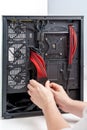 A technician assembling computer hardware inside a sleek black case with vibrant red cables Royalty Free Stock Photo