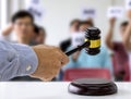 The person carrying the auction holds a wooden hammer in his hand to make a bid to sell the product