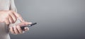 Person casually holding a smartphone, engaging with the touch screen in a subtle motion. Grey background ann providing generous Royalty Free Stock Photo