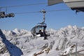 Person on chair lift in ski resort with snowcapped mountain peaks in the background Royalty Free Stock Photo