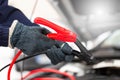 Person charging car battery with jumper cable in close up.