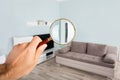 Person Checking Living Room Using Magnifying Glass