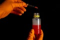 Person chemist holds test tube of glass in his hand with red acid. Mixing chemicals