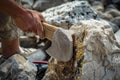 person chipping stone against a boulder to make an axe