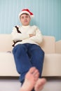 Person in Christmas cap sits on sofa Royalty Free Stock Photo