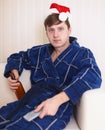 Person in christmas hat sits on sofa with beer Royalty Free Stock Photo