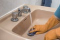 A person cleaning the bathroom sink with a glove. Royalty Free Stock Photo