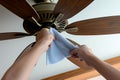 person cleaning ceiling fan blades with a microfiber cloth Royalty Free Stock Photo