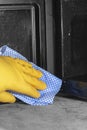 Person cleaning the inside of a microwave oven with a blue and white cloth Royalty Free Stock Photo