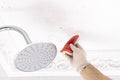Person cleaning small mold stains on shower ceiling with gloves Royalty Free Stock Photo