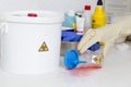 Person cleaning a waste container labeled as biological risk