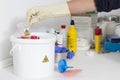 Person cleaning a waste container labeled as biological risk