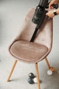 Person cleans chair with handheld wireless vacuum cleaner