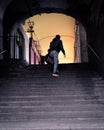 Person climbing dark stairs towards an illuminated gallery