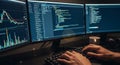 Person coding on multiple monitors displaying data charts and programming code at desk Royalty Free Stock Photo