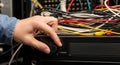 A person connecting a cable to a network switch in a server room Royalty Free Stock Photo
