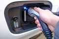 Person connecting a charging cable to an electric car