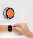A person controlling a smart thermostat from a smart watch