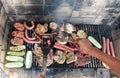 Person cooking assorted meat and vegetables on BBQ Royalty Free Stock Photo