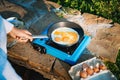 Person cooking eggs on camping stove Royalty Free Stock Photo