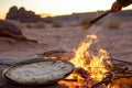 person cooking flatbread over an open fire in the desert Royalty Free Stock Photo