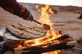 person cooking flatbread over an open fire in the desert Royalty Free Stock Photo