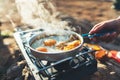 Person cooking fried eggs in nature camping outdoor, cooker prepare scrambled breakfast picnic on metal gas stove, tourism Royalty Free Stock Photo