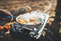 Person cooking fried eggs in nature camping outdoor, cooker prepare scrambled omelette breakfast picnic on metal stove, tourist Royalty Free Stock Photo