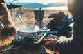 Person cooking nature camping outdoor, cooker prepare breakfast picnic on metal gas stove, hot tea outside; campsite lifestyle