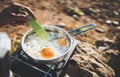 Person cooking omelette eggs in nature camping outdoor, cooker prepare breakfast picnic on metal gas stove, tourism recreation Royalty Free Stock Photo