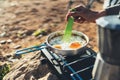 Person cooking scrambled eggs in nature camping outdoor, cooker prepare breakfast picnic on metal gas stove, tourism recreation Royalty Free Stock Photo
