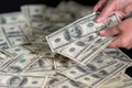 Person counting 100 dollar bills onto a pile Royalty Free Stock Photo